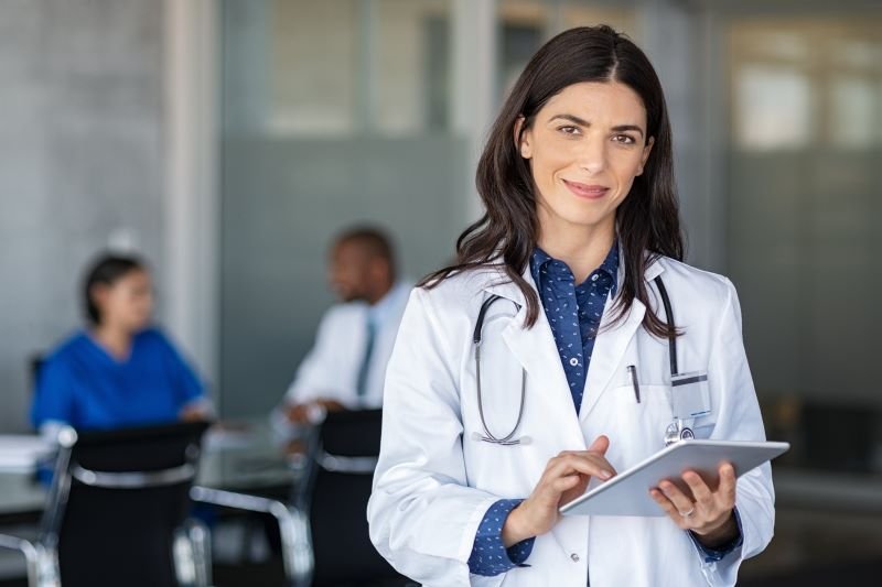 Profissional médica operando um tablet e olhando confiantemente.